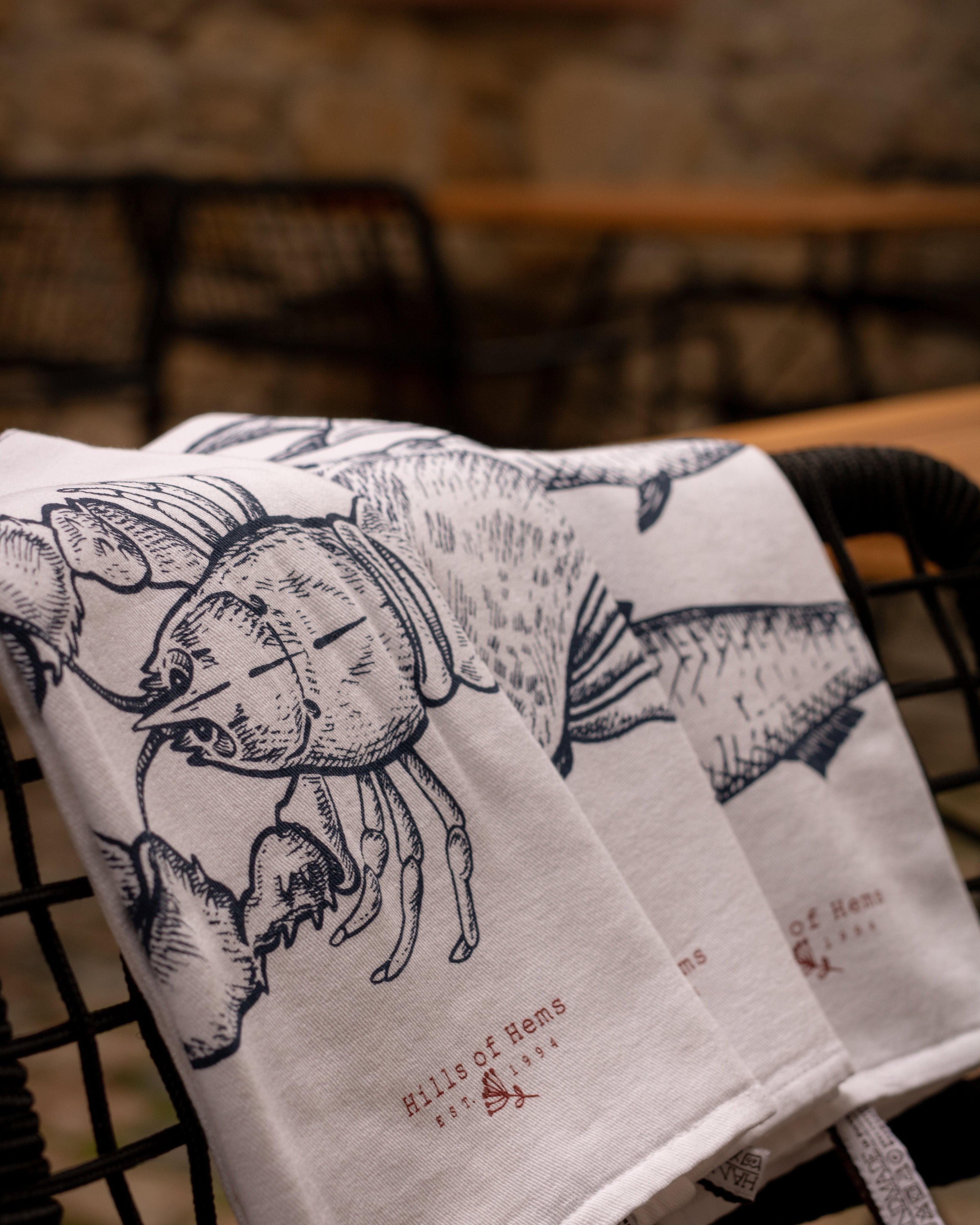 Geschirrtücher mit Meerestiere Print liegen auf einem Stuhl